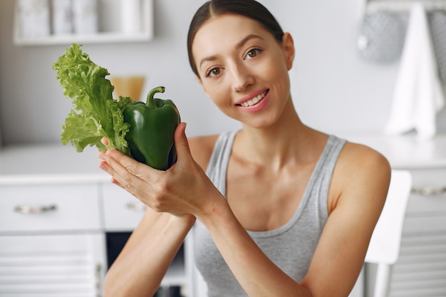 Schöne und sportliche Frau in einer Küche mit Gemüse