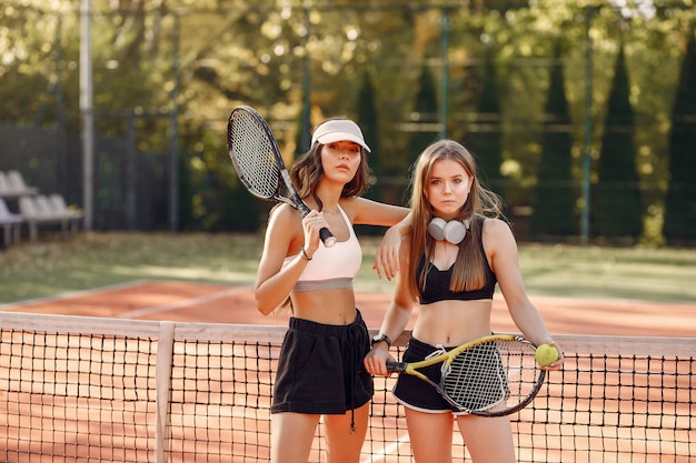 Schöne und stilvolle Mädchen auf dem Tennisplatz