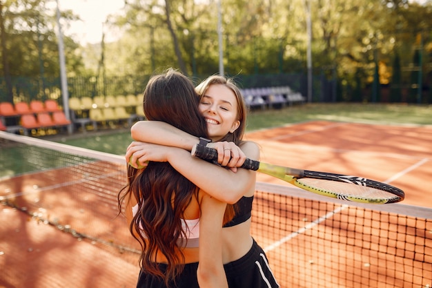 Schöne und stilvolle Mädchen auf dem Tennisplatz