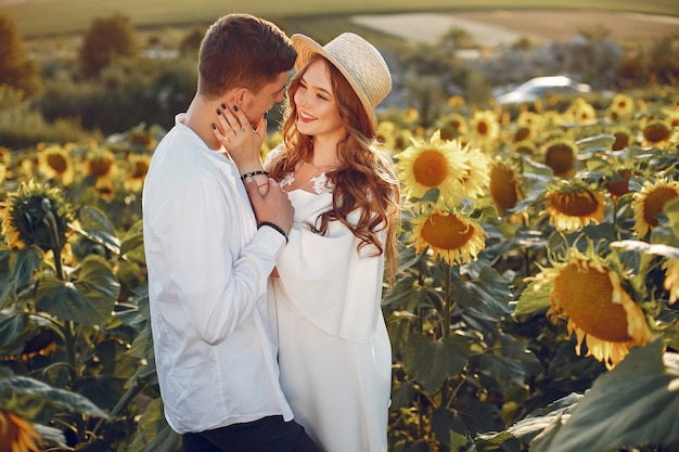 Schöne und stilvolle Paare auf einem Gebiet mit Sonnenblumen