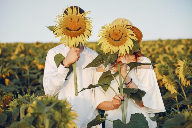 Schöne und stilvolle Paare auf einem Gebiet mit Sonnenblumen