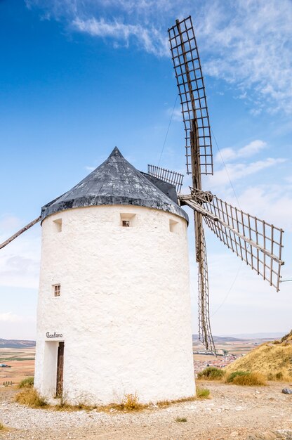 Schöne vertikale Aufnahme einer weißen Steinwindmühle am blauen Himmel in Consuegra, Spanien
