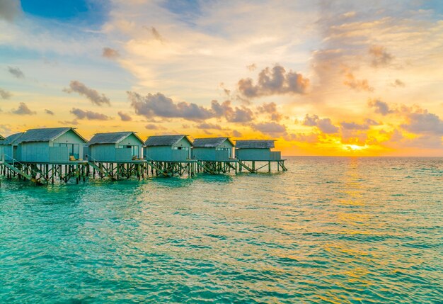 Schöne Wasser Villen in tropischen Malediven Insel bei der Sonnenuntergang Zeit