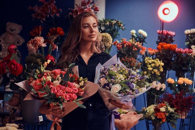 Schöne weibliche Floristin zeigt erstaunliche Blumensträuße im Blumenladen