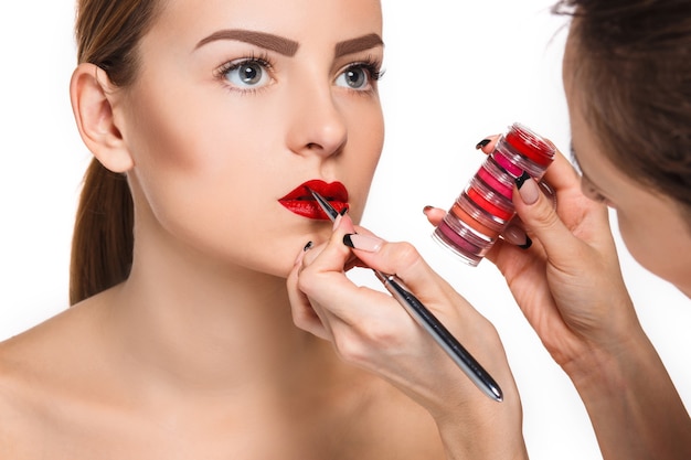 Schöne weibliche Lippen mit Make-up und Pinsel auf Weiß. Maskenbildner Arbeitsprozess