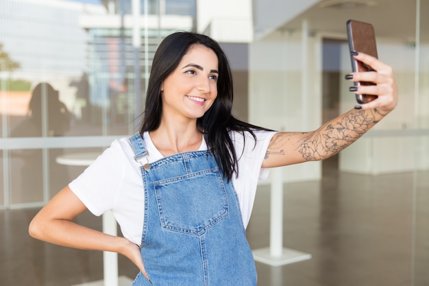 Schöne zufriedene Frau, die selfie mit Smartphone nimmt