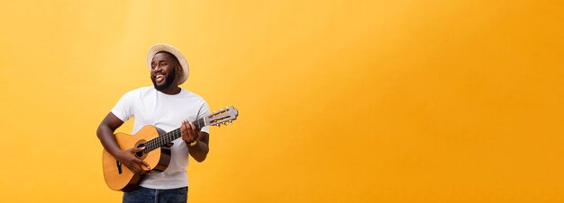 Schöner afrikanisch-amerikanischer Gitarrist im Retro-Stil, der Akustikgitarre spielt, isoliert auf gelbem Hintergrund
