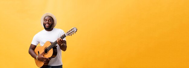 Schöner afrikanisch-amerikanischer Gitarrist im Retro-Stil, der Akustikgitarre spielt, isoliert auf gelbem Hintergrund