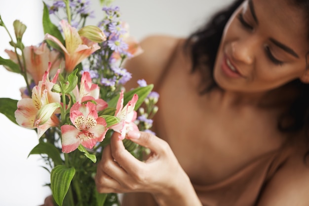 Schöner afrikanischer weiblicher Florist, der Blumenstrauß macht. Konzentrieren Sie sich auf Alstroemerien.