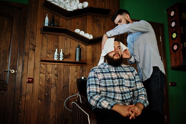 Kostenloses Foto schöner bärtiger mann im friseursalon friseur bei der arbeit kopf waschen