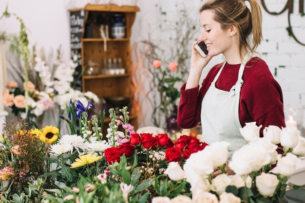 Schöner Blumenhändler, der über Smartphone spricht