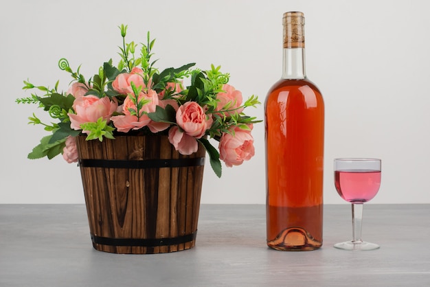 Schöner Blumenstrauß und Flasche Roséwein auf grauem Tisch