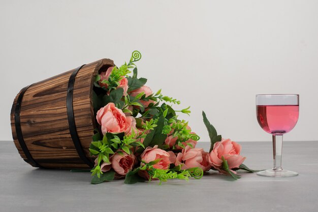 Schöner Blumenstrauß und Glas Roséwein auf grauem Tisch.