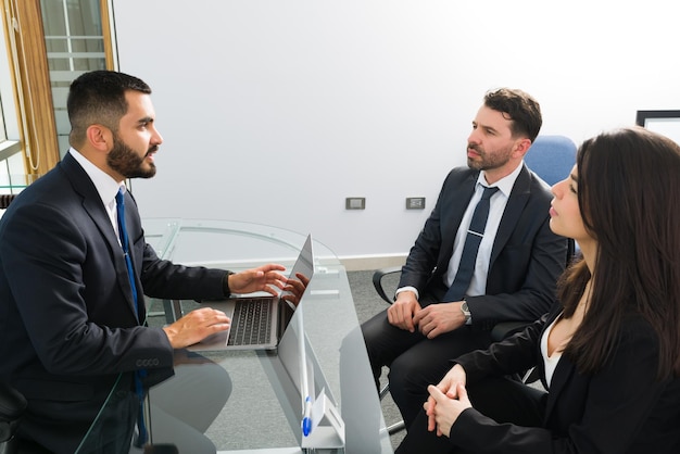 Schöner Chef, der mit seinen professionellen Mitarbeitern in seinem Büro in einem Business Center über Produktivität und neue Arbeitsaufgaben spricht