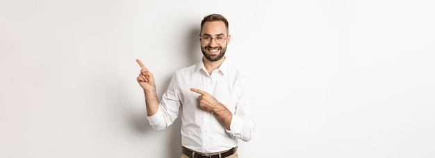 Schöner erfolgreicher Geschäftsmann, der mit dem Finger nach rechts zeigt und Werbung mit erfreutem Gesicht weiß zeigt