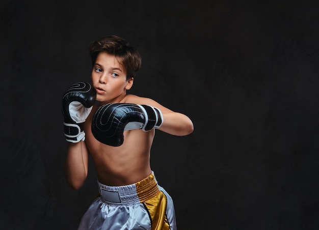 Schöner, hemdloser junger Boxer bei Boxübungen, konzentriert auf den Prozess mit ernster, konzentrierter Gesichtsbehandlung.