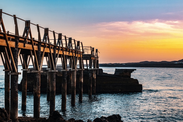 Schöner hölzerner Pier an der Küste des Meeres mit einem schönen Sonnenuntergang