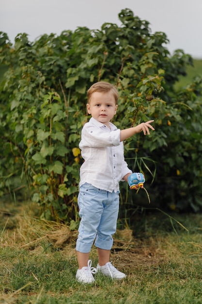 Schöner Junge, der mit Blasen am sonnigen Tag im Garten spielt.