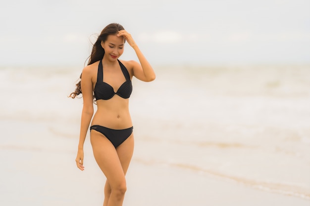 Schöner junger asiatischer Frauenabnutzungsbikini des Porträts auf dem Strandseeozean