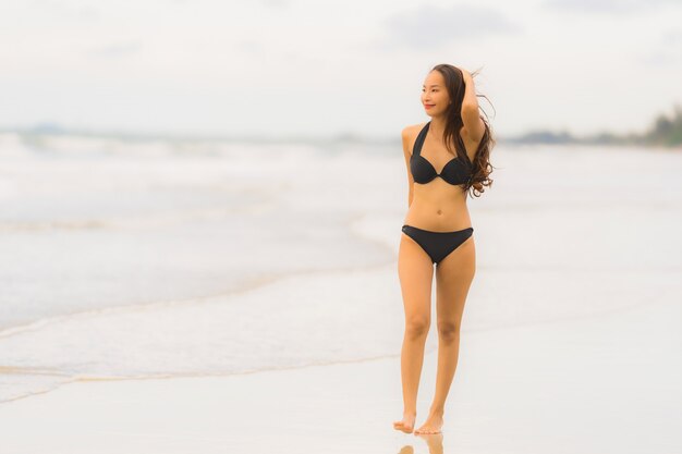 Schöner junger asiatischer Frauenabnutzungsbikini des Porträts auf dem Strandseeozean