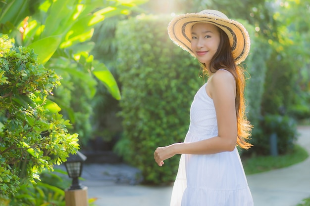 Schöner junger asiatischer Frauenweg des Portraits mit dem glücklichen Lächeln und entspannen sich im Park