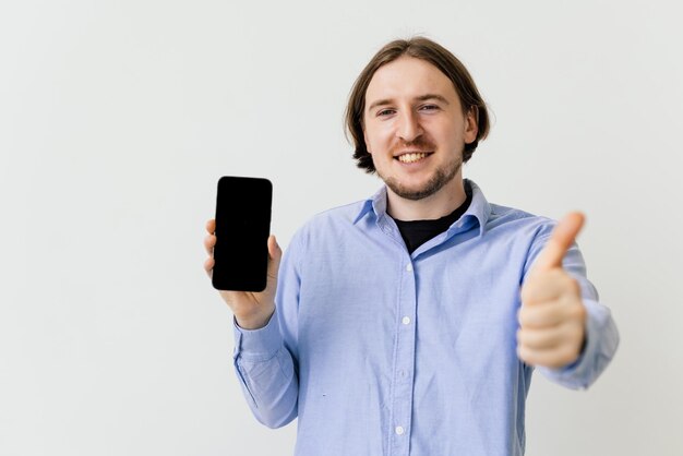 Schöner Kerl, der mit dem Finger auf ein leeres Bildschirmtelefon auf weißem Hintergrund zeigt
