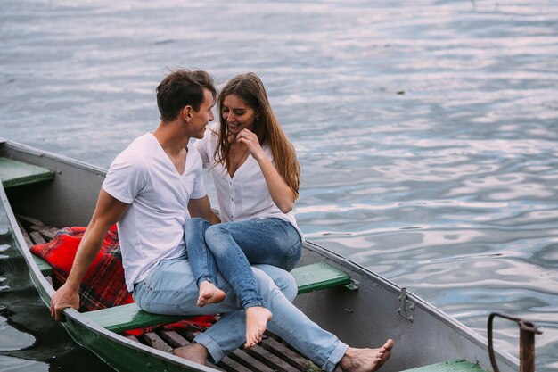 Schöner Kerl und schönes Mädchen ruhen in einem Boot auf dem See