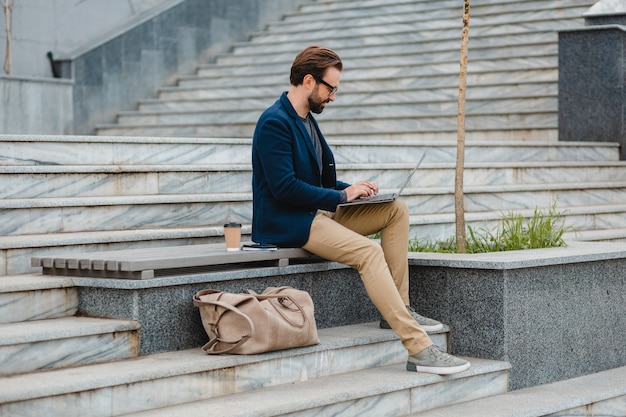 Schöner lächelnder bärtiger Mann mit Brille, der am Laptop arbeitet