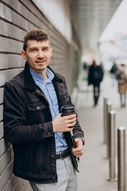 Schöner Mann, der auf der Straße steht und Laptop hält
