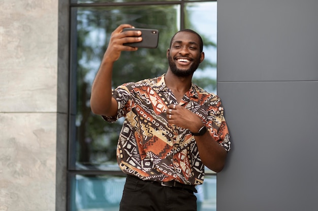 Schöner Mann, der im Freien ein Selfie mit einem modernen Smartphone macht