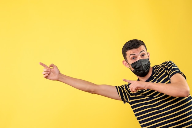 Kostenloses Foto schöner mann der vorderansicht in der schwarzen maske, die auf linken gelben isolierten hintergrund zeigt