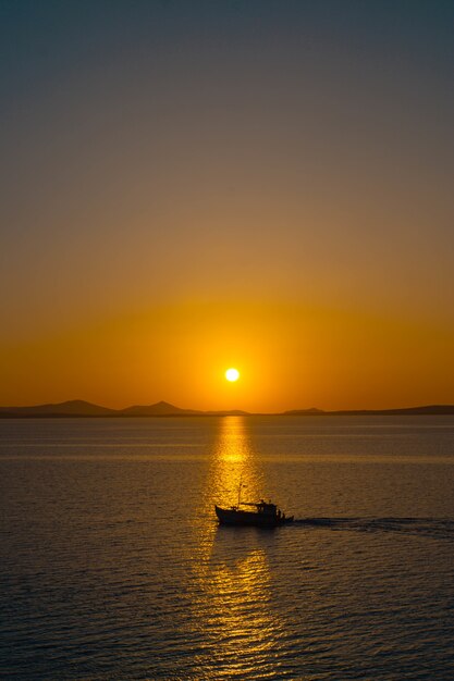 Schöner Ozean mit einem kleinen Boot, das auf Wasser bei Sonnenuntergang schwimmt