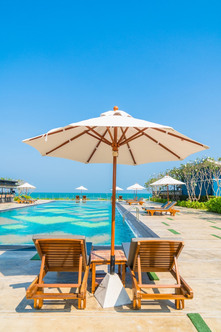 Kostenlose Foto schöner regenschirm und stuhl rund um den pool in hotel und resort