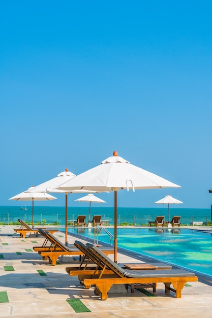 Schöner Regenschirm und Stuhl rund um den Pool in Hotel und Resort