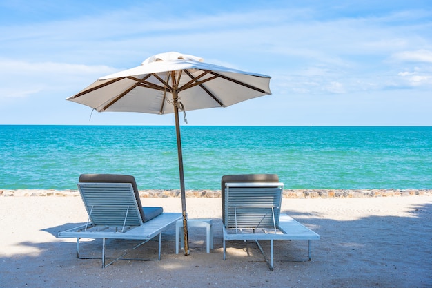Schöner Regenschirm und Stuhl um Strandseeozean mit blauem Himmel für Reise