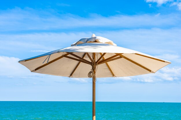 Schöner Regenschirm und Stuhl um Strandseeozean mit blauem Himmel für Reise