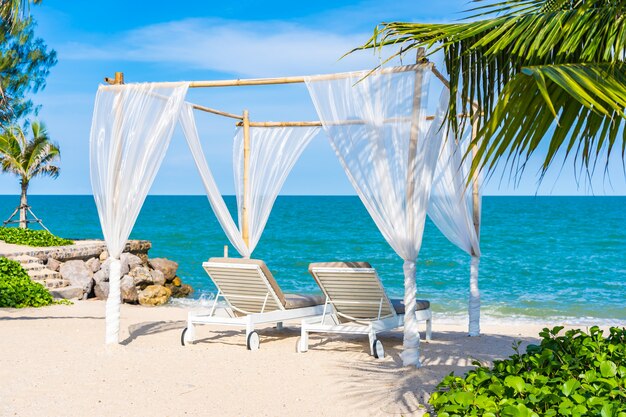 Schöner Regenschirm und Stuhl um Strandseeozean mit blauem Himmel für Reise