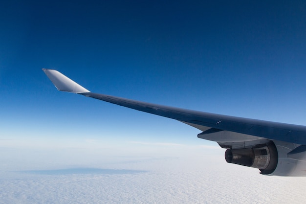 Schöner Schuss aus einem Flugzeugfenster der Flügel über den Wolken