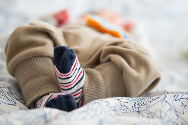 Schöner Schuss der niedlichen kleinen Füße eines Babys, das auf einem Bett liegt