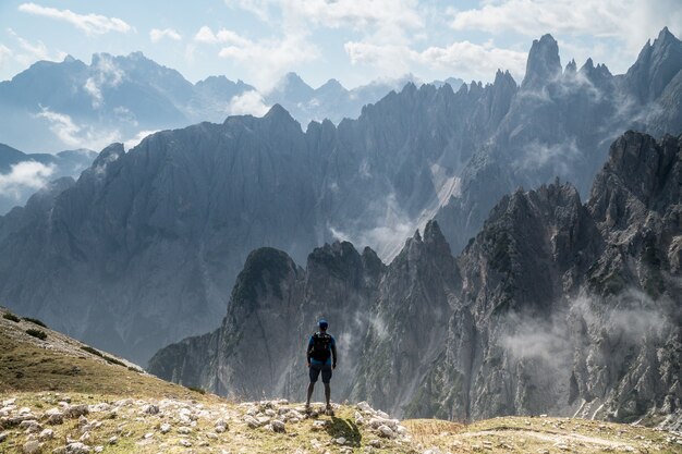 Schöner Schuss der Person, die auf einem Felsen steht, der Drei-Gipfel-Naturpark in Toblach, Italien betrachtet