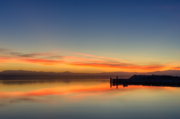 Schöner Schuss der Reflexion des orangefarbenen Sonnenuntergangshimmels im Wasser