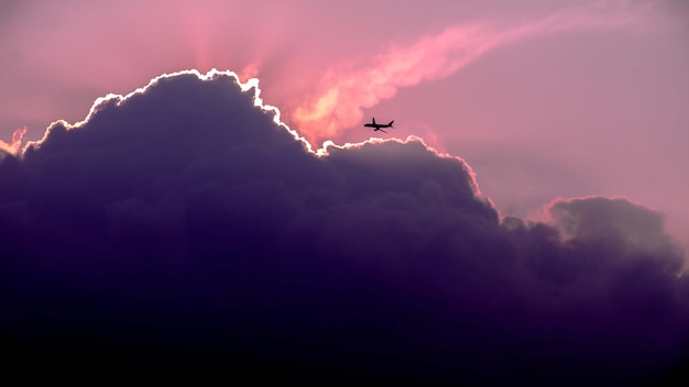 Schöner Schuss der Silhouette des Flugzeugs, das im Himmel während des Sonnenaufgangs fliegt
