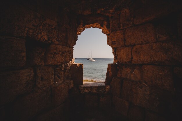 Schöner Schuss des Meeres mit Segelbooten von der Innenseite eines Lochs in einer Steinmauer