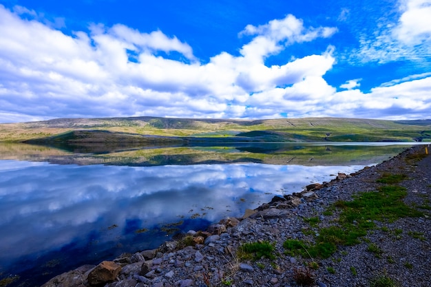 Schöner Schuss des Wassers nahe felsigem Ufer und Berg in der Ferne mit Wolken am Himmel