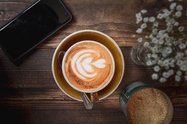 Schöner Schuss einer Tasse Cappuccino mit einem weißen Herzmuster auf einem Holztisch