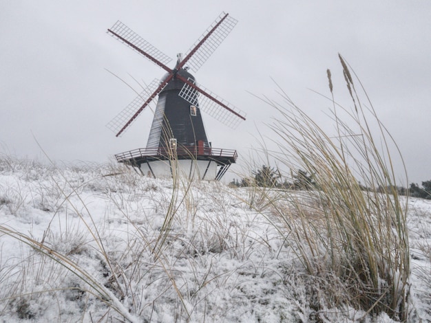 Schöner Schuss einer Windmühle in der Mitte eines Winterfeldes