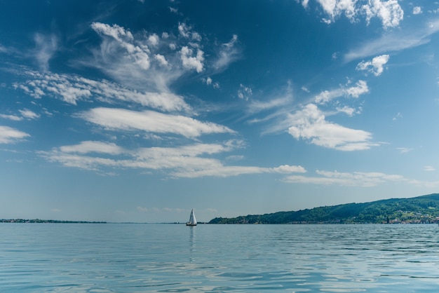 Schöner Schuss eines Bootes, das in einem ruhigen Meer mit Hügeln auf der rechten Seite segelt