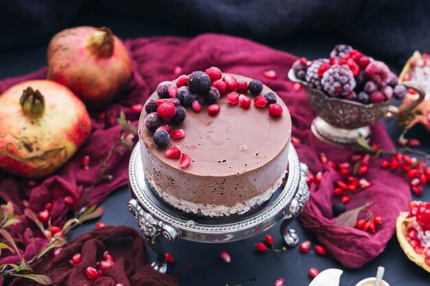 Schöner Schuss eines rohen veganen Kuchens mit Beeren und Granatapfelkernen verstreut um