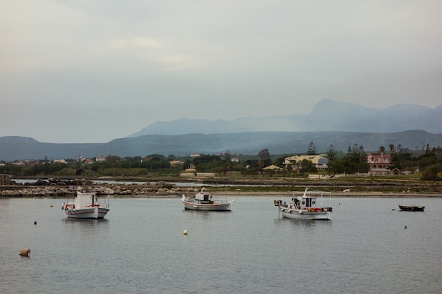 Kostenloses Foto schöner schuss von booten auf dem wasser mit gebäuden und bergen in der ferne