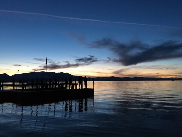 Schöner Schuss von Leuten, die auf dem Deck stehen, umgeben von Wasser bei Sonnenuntergang